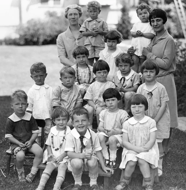 A black-and-white vintage group photo of children and their teachers